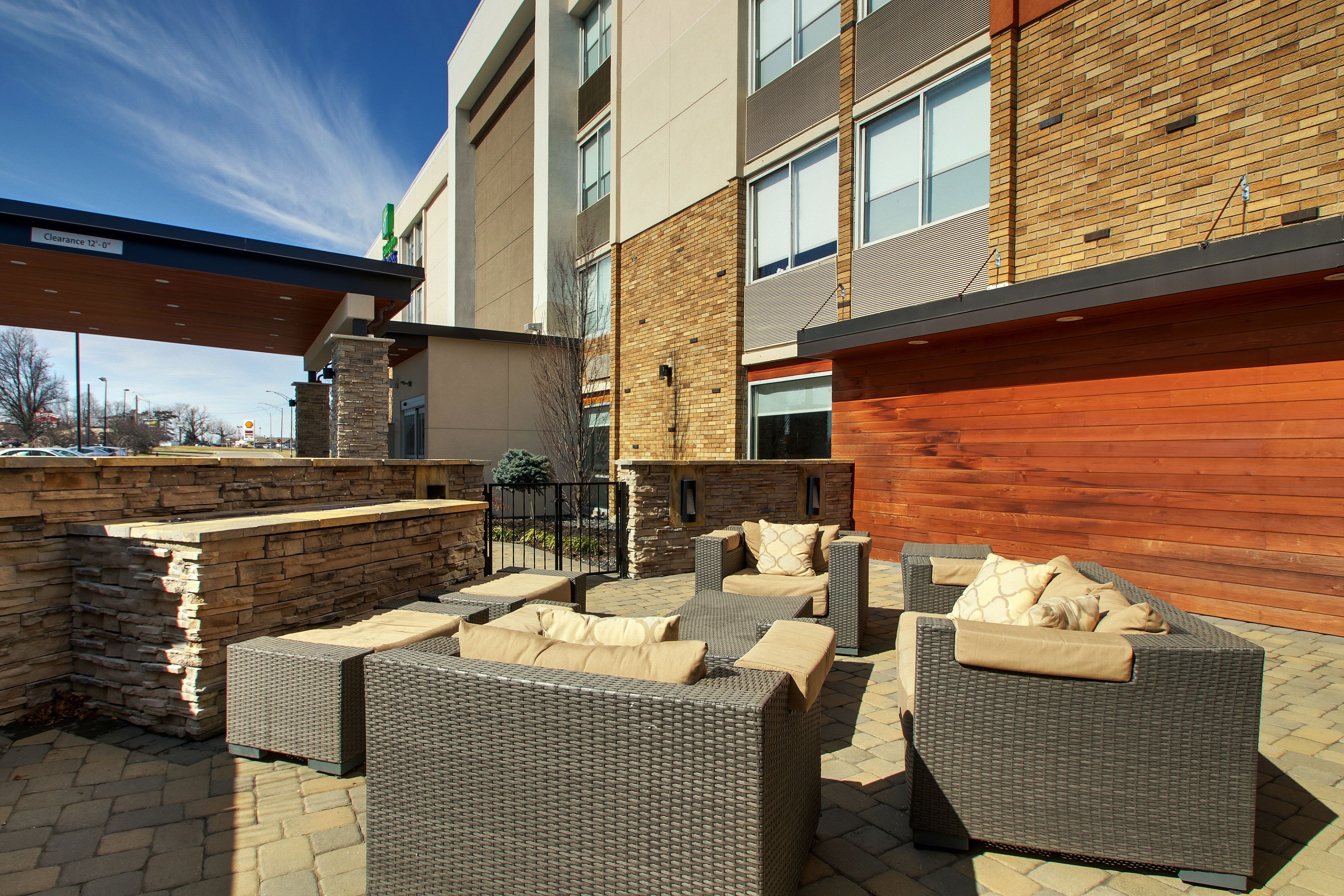 An outdoor seating area with wicker furniture and a stone wall.