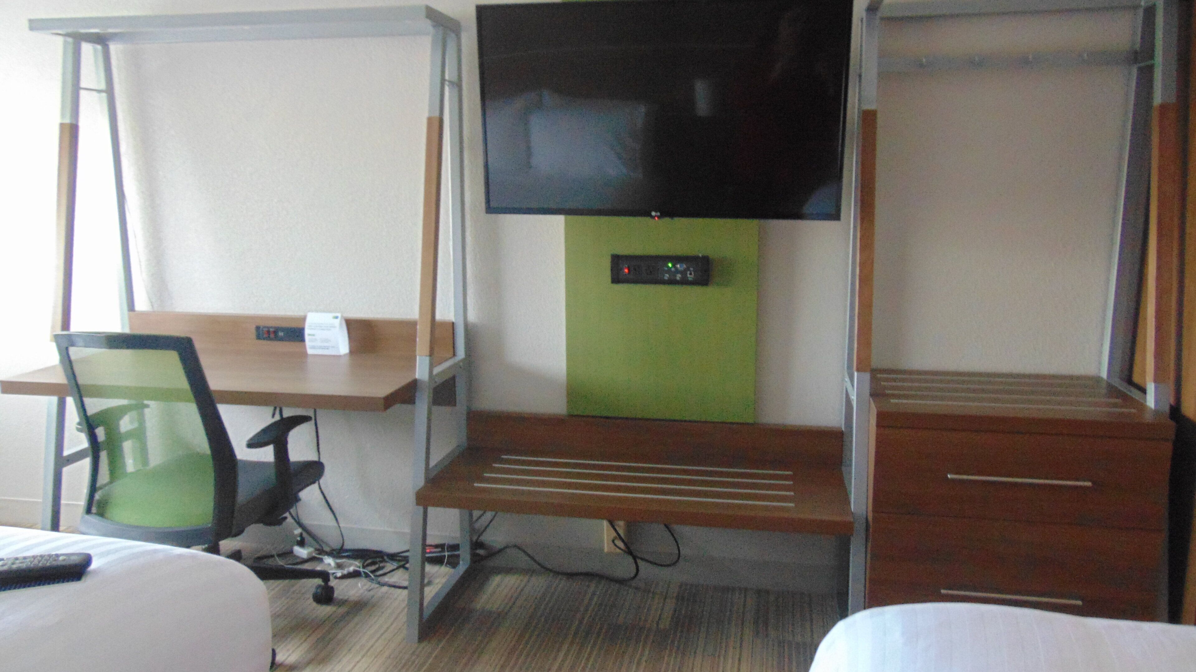 Une chambre d’hôtel équipée d’un bureau, d’une chaise, d’une télévision et d’un petit placard.