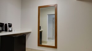 Ein Badezimmer mit Spiegel, einer Kaffeemaschine und einem schwarzen Schrank.