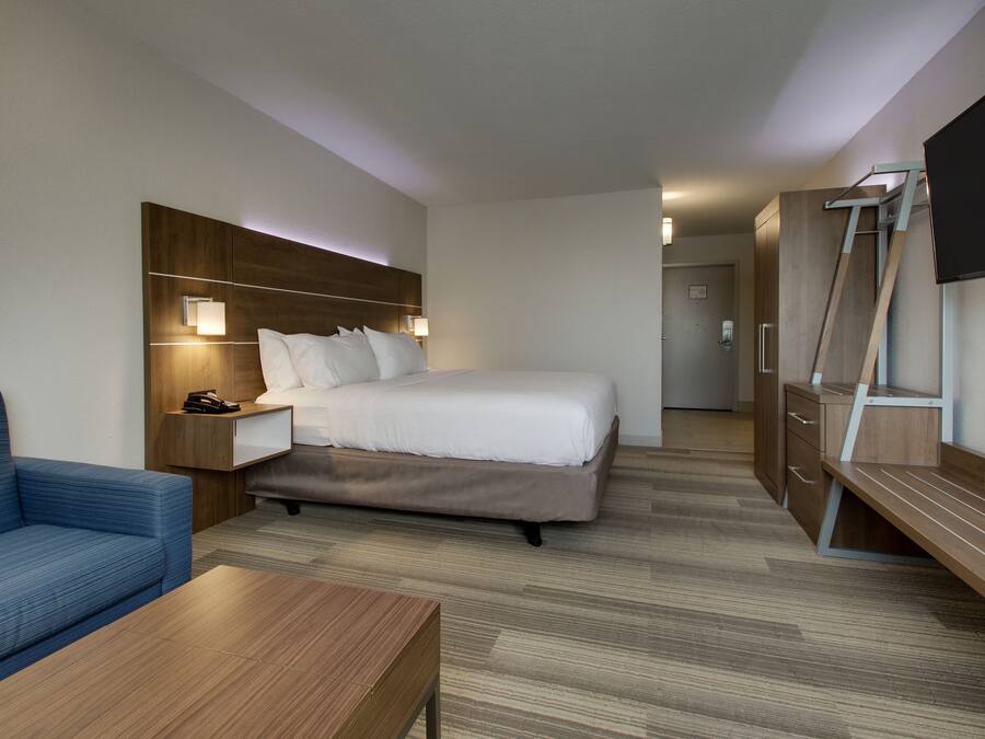 Una habitación de hotel con cama, escritorio, silla, televisor y armario.