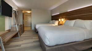 Ein Hotelzimmer mit zwei Betten, einem Schreibtisch, einem Fernseher und einem Holzkopfende.