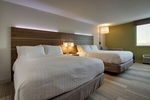 Habitación de hotel con dos camas, cabecero de madera, lámparas de noche, ventana y aire acondicionado.