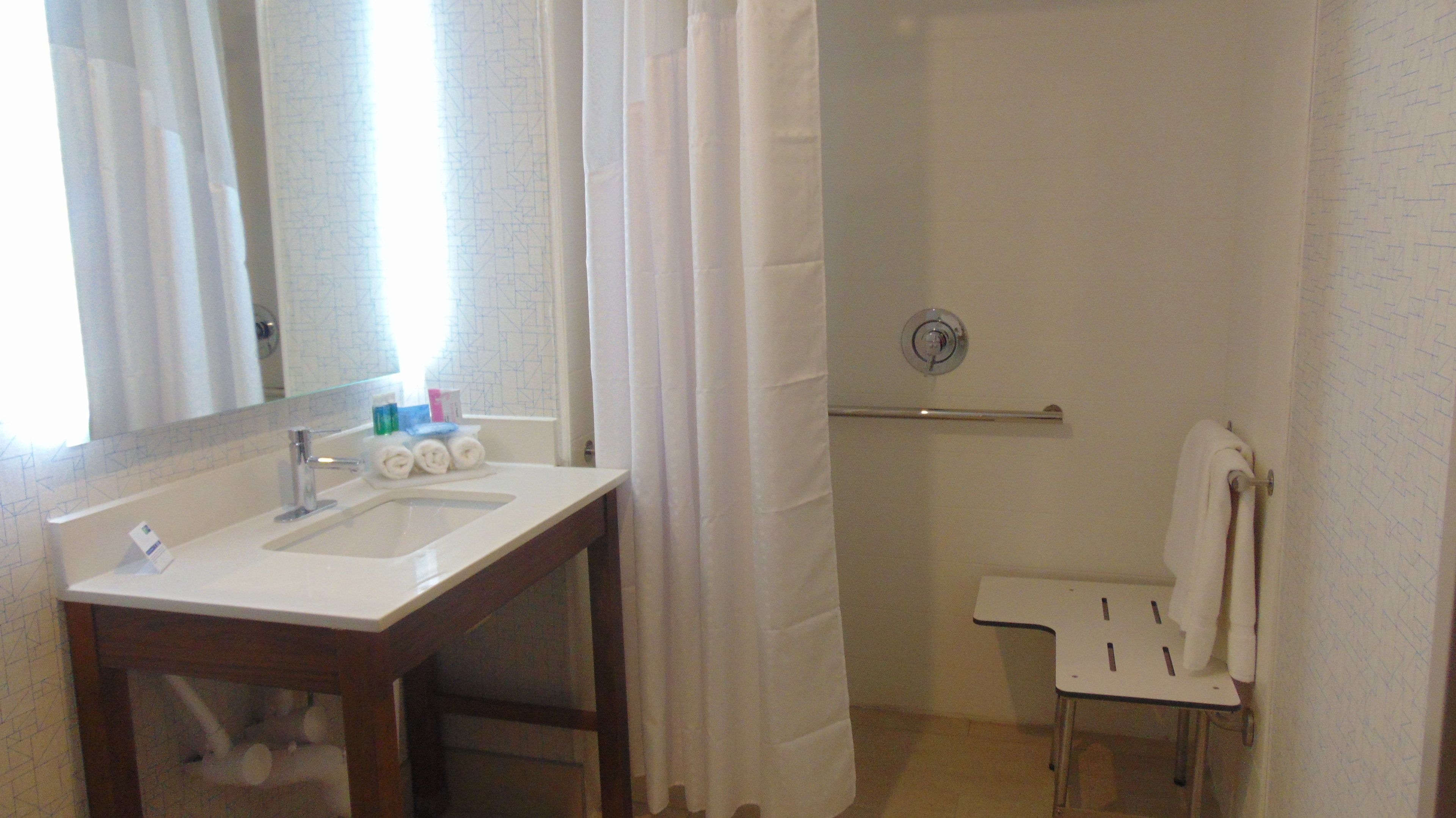 Un baño con lavamanos, espejo y ducha.