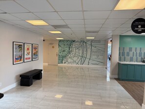 A lobby with a map mural, framed artwork, a bench, and a cafe sign.