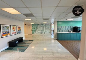 Una hall d'albergo con un murale raffigurante una mappa, un angolo caffetteria e una panca.