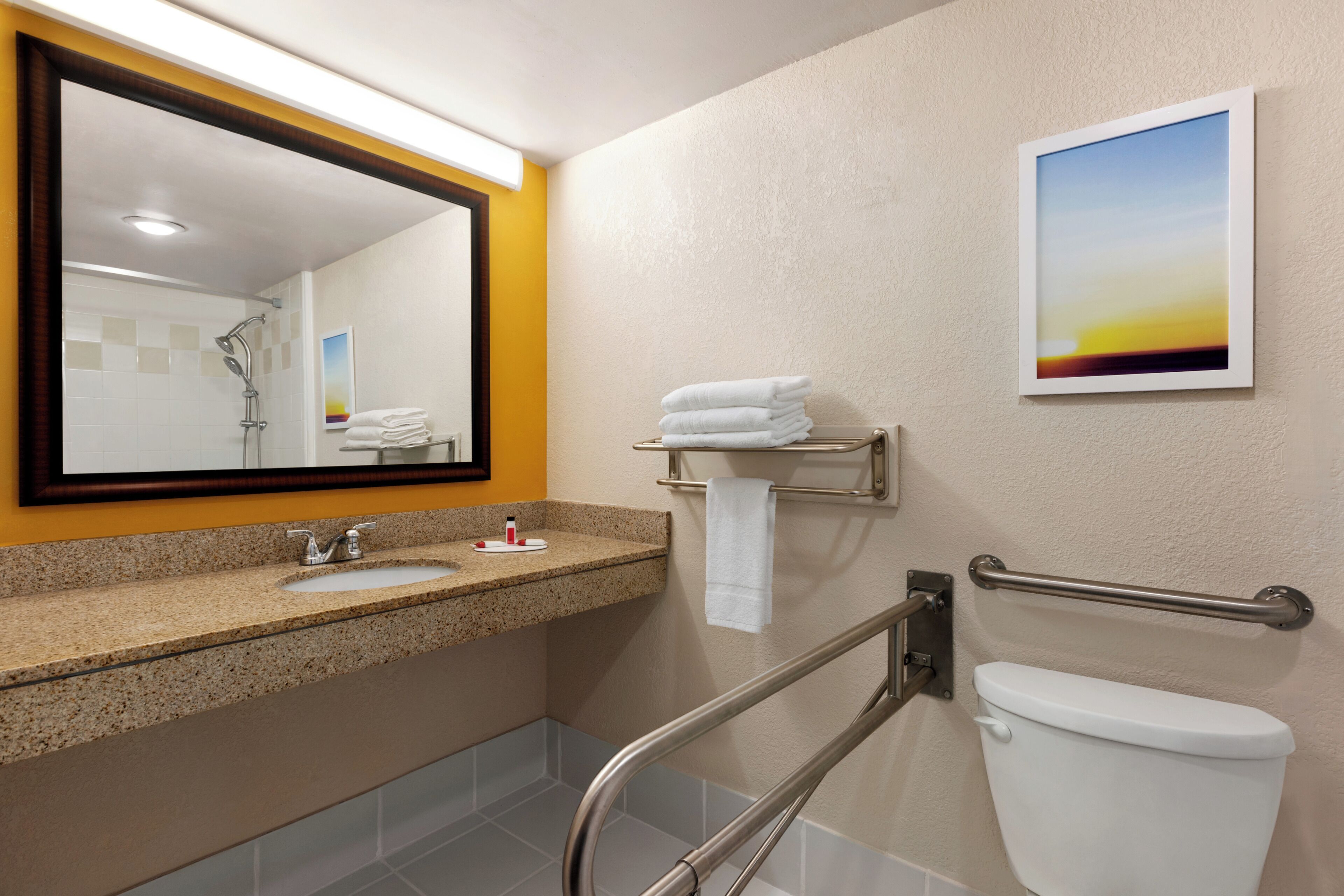 Un baño con lavamanos, espejo, toallero y retrete.