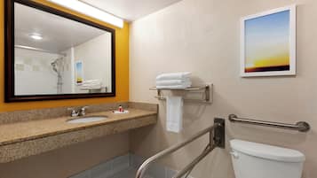Un baño con lavamanos, espejo, toallero y retrete.