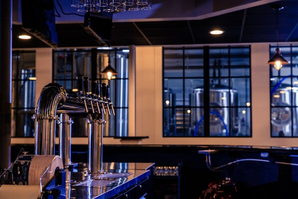 A bar area with a beer tap system, a counter, and industrial-style windows in the background.