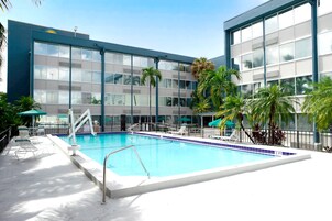 Una piscina al aire libre, sombrillas, sillones reclinables de piscina
