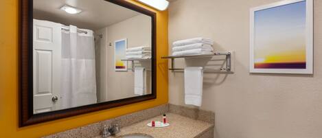 A bathroom with a sink, mirror, towel rack, toilet, and a painting on the wall.