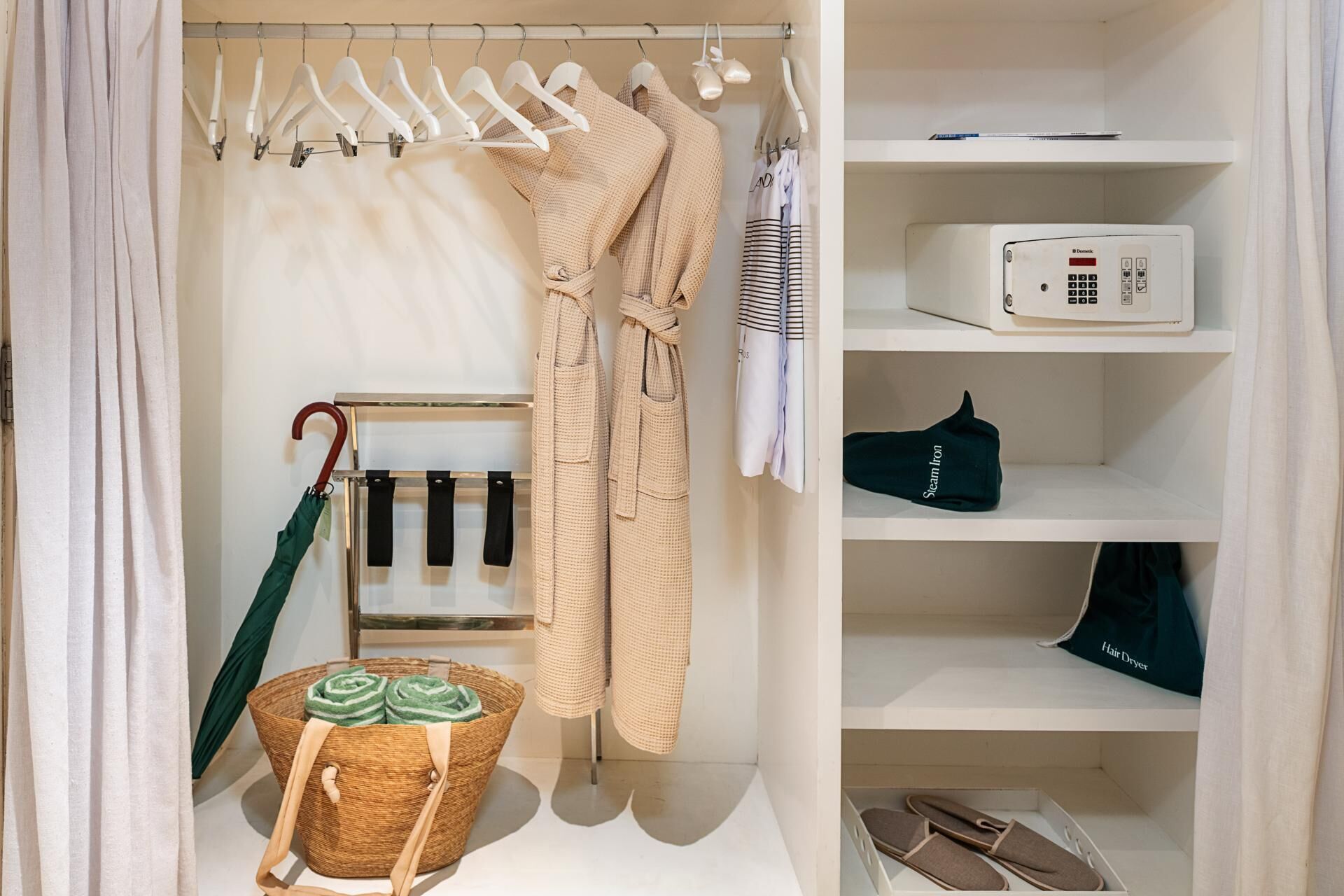 A neatly organized closet with hanging robes, a hairdryer, and a basket with towels.