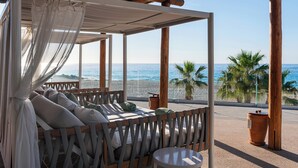 A beachside lounge with a wooden bench and a small table, overlooking the sea. - Paradisus Los Cabos – Adults Only – All Inclusive – The Leading Hotels of the World (San José del Cabo)