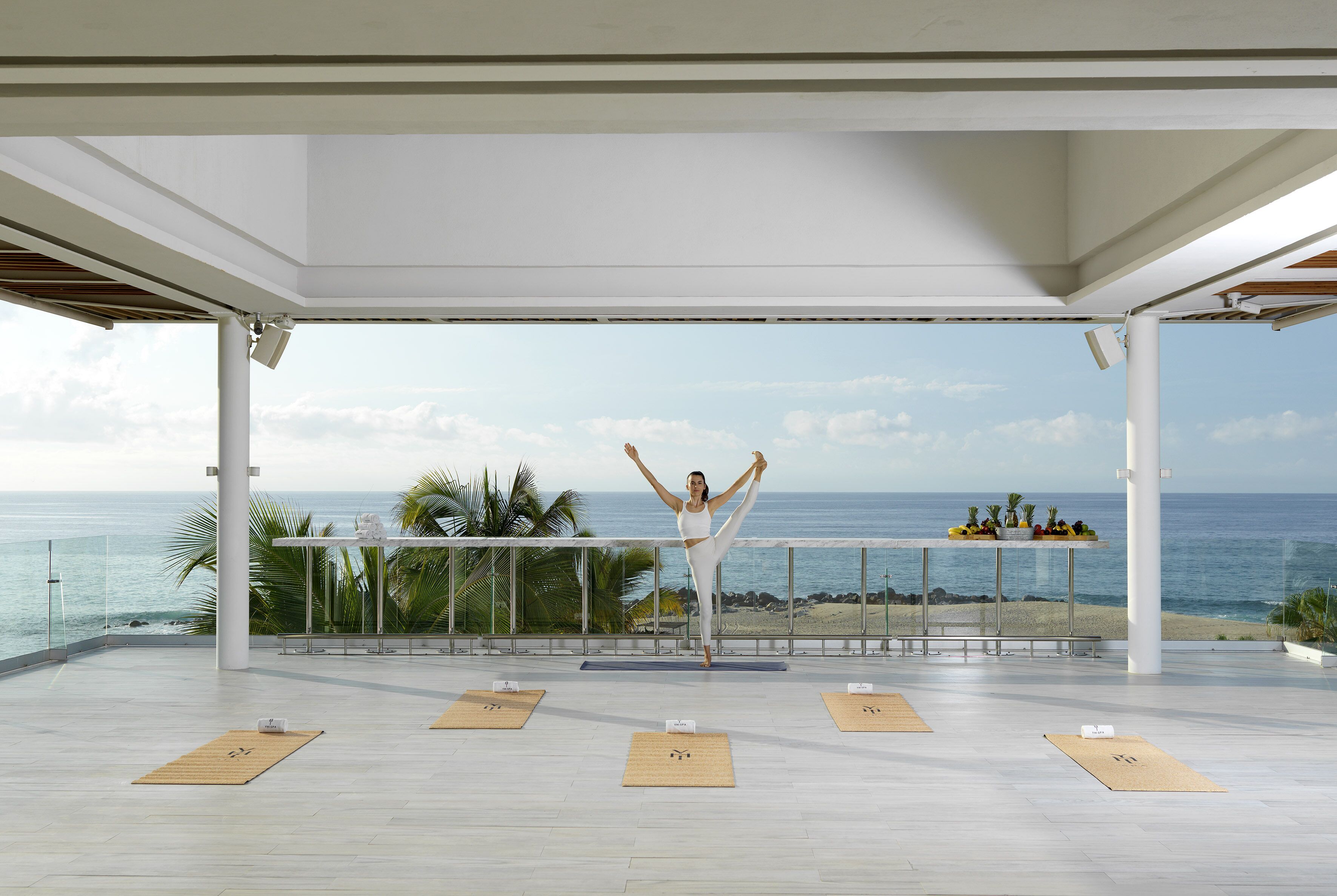 A yoga mat with a person performing a yoga pose on a balcony overlooking the ocean.