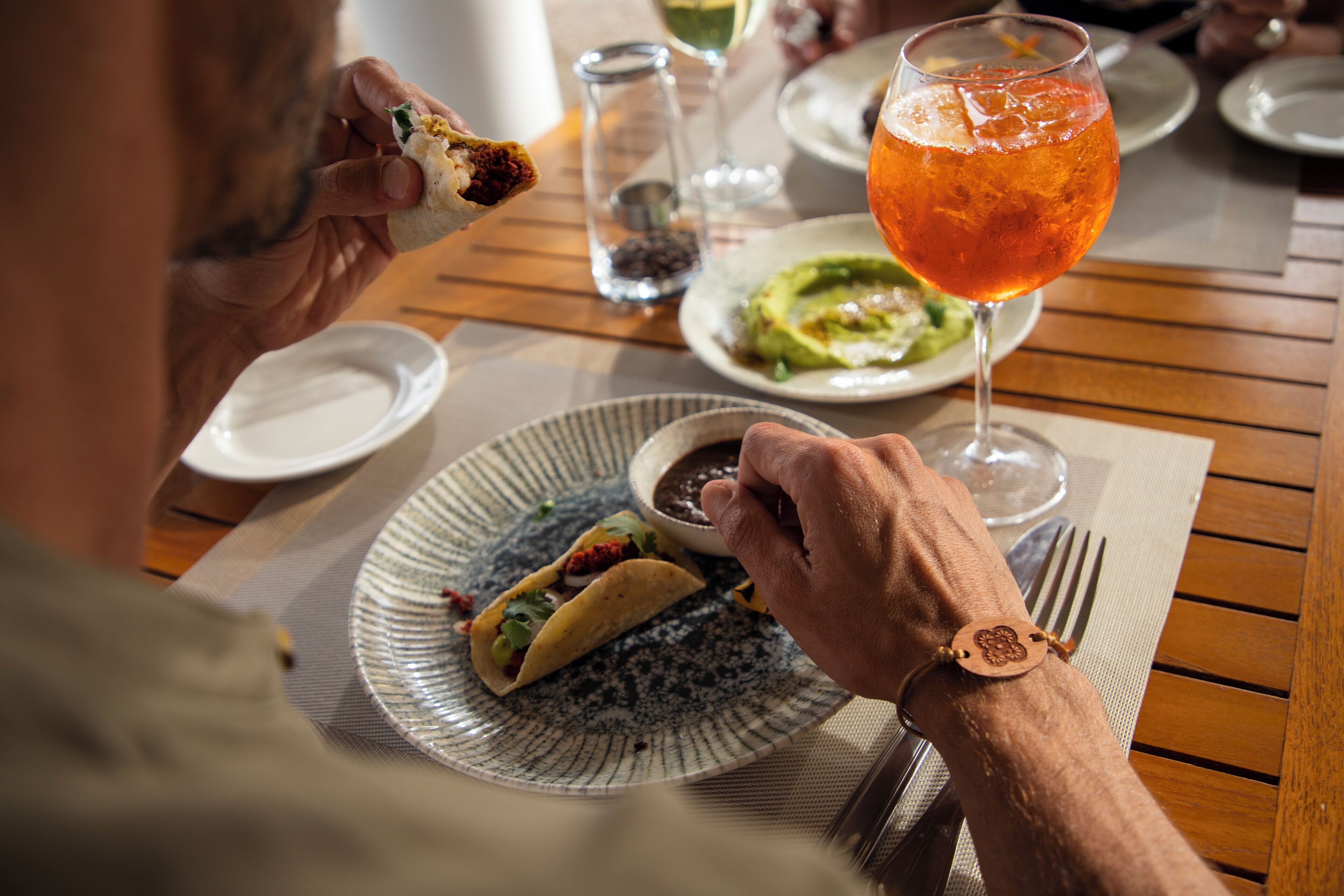 Et spisebord med tacos, et glas appelsindrik og en skål salsa.