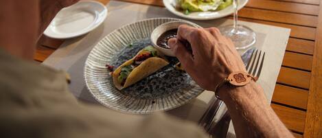 Et spisebord med tacos, et glas appelsindrik og en skål salsa.