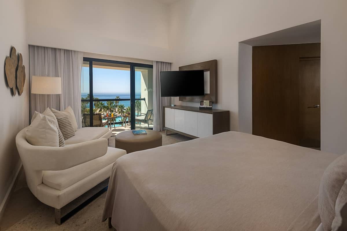 Ein Hotelzimmer mit Bett, einer Couch, einem Fernseher und Meerblick.