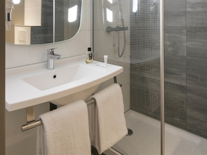 A modern bathroom with a white sink, a mirror, and a glass shower enclosure. - ibis Tilburg (Tilburg)