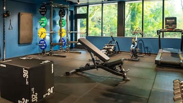 Un gimnasio con equipo de levantamiento de pesas, una banca y máquinas de cardio.