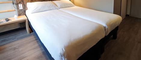 A neatly made bed with white linens in a hotel room.