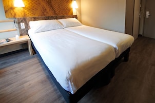 Una cama bien hecha con sábanas blancas en una habitación de hotel.