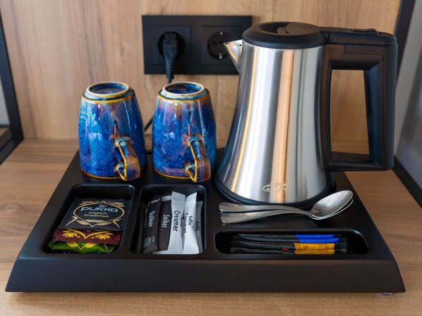 A tray with a coffee maker, two mugs, a spoon, and some packaged food items. - ibis Tilburg (Tilburg)