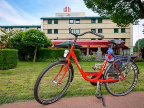 A red bicycle with a basket and a seat, parked on a paved path. - ibis Tilburg (Tilburg)