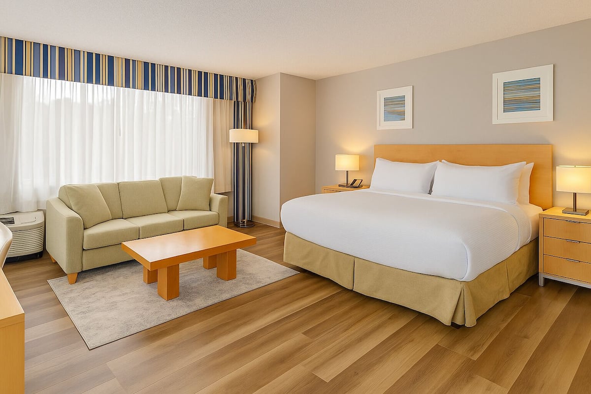 Ein Hotelzimmer mit einem Bett, einem Sofa, einem Couchtisch, einem Nachttisch und einer Lampe.