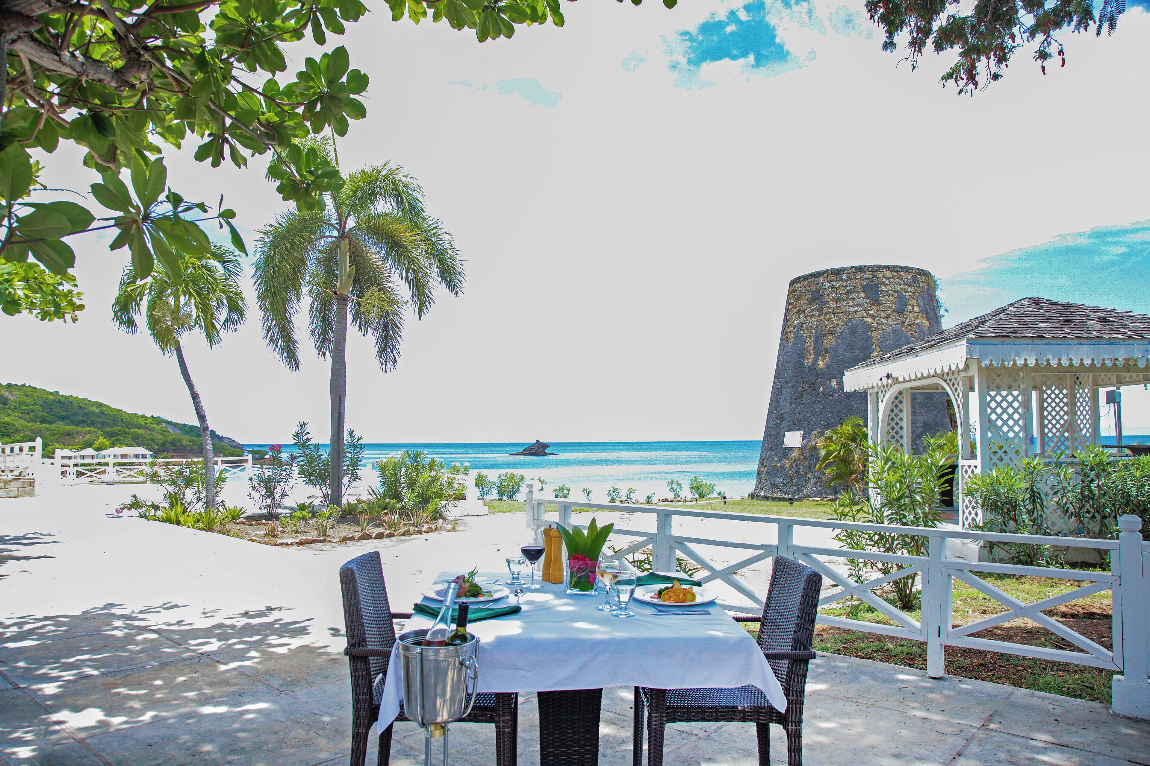 Une table dressée pour le dîner, avec vue sur la plage et l’océan.