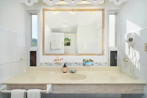 Un baño con un espejo grande, un lavabo, un secador de pelo y una ventana.