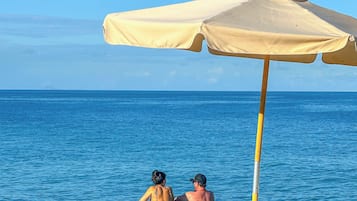 Deux personnes dans une piscine, avec un parasol de plage.
