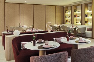 Ein modernes Restaurant mit runden Tischen, gepolsterten Sitzplätzen und einem warmen, holzigen Ambiente.