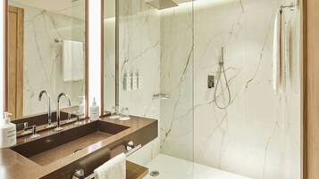 Un bagno moderno con una parete in marmo, uno specchio grande, un mobile doppio lavabo e una cabina doccia.