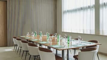 Un salón de conferencias con una larga mesa dispuesta para una reunión, rodeado de sillas.