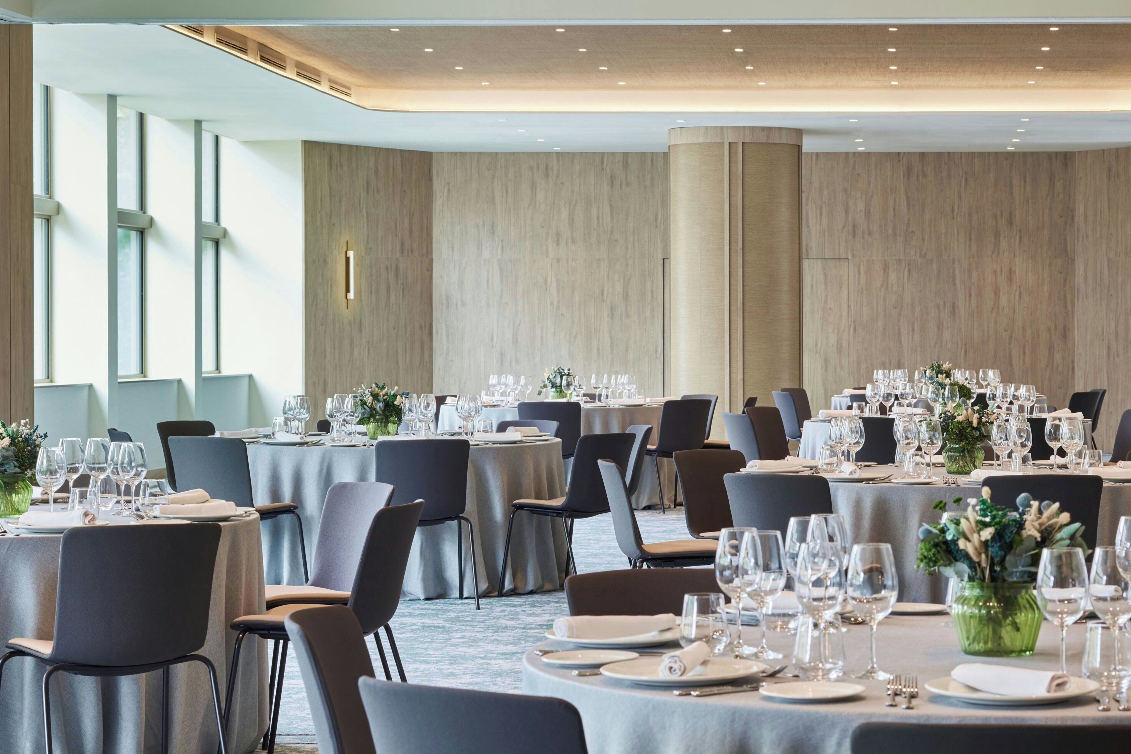 A banquet hall with round tables set for dining, equipped with chairs and table settings.
