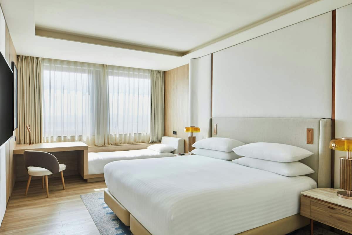 Une chambre d’hôtel avec deux lits, un bureau, une chaise, une télévision et une lampe.