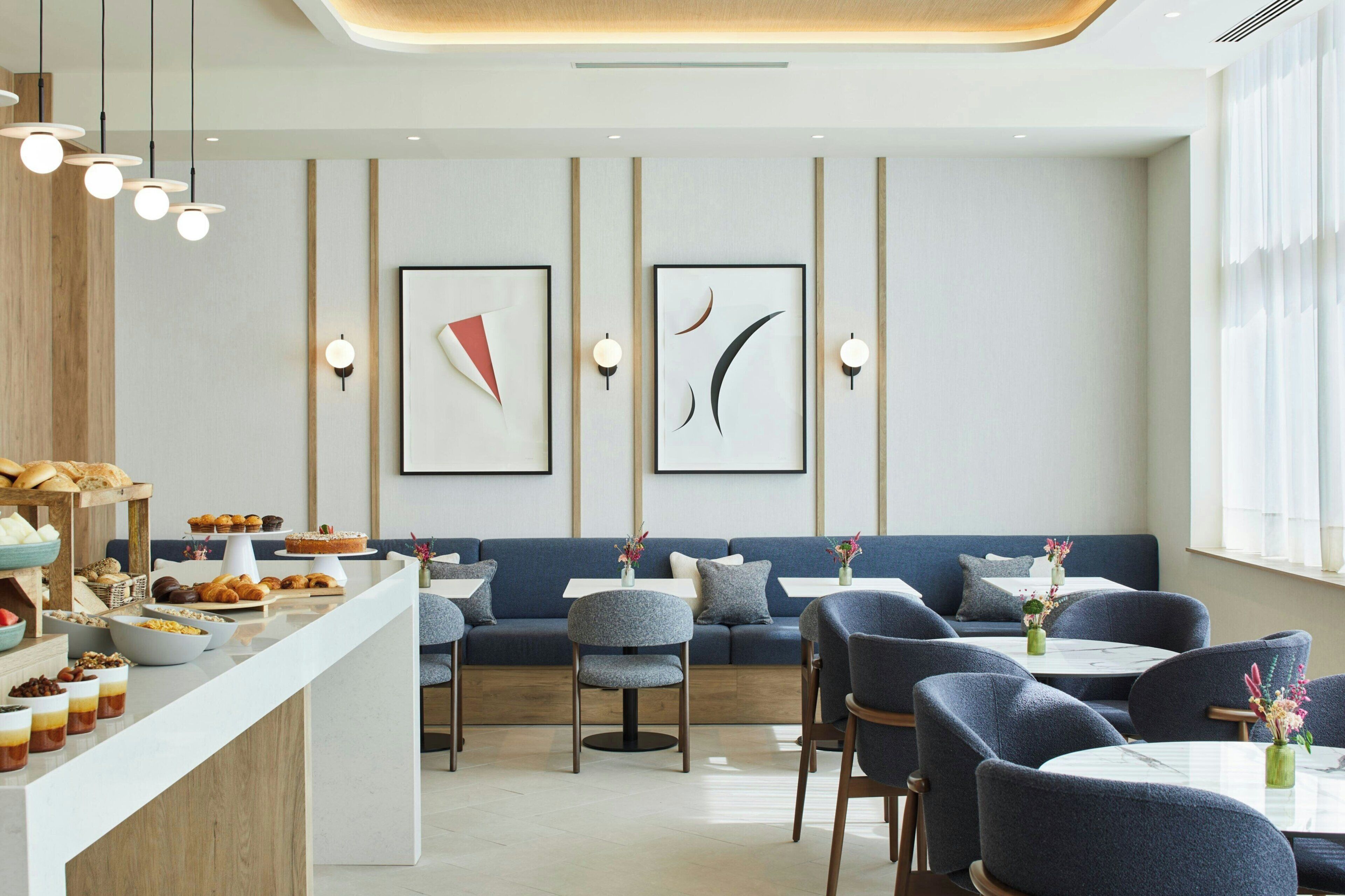 A modern dining area with a long counter, seating arrangements, and wall-mounted artwork.