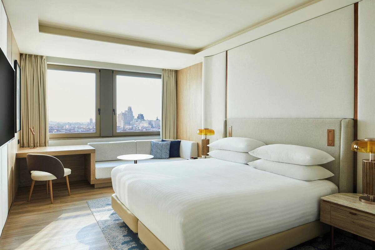 Une chambre d’hôtel avec un grand lit, un bureau, une chaise et une vue sur la ville.
