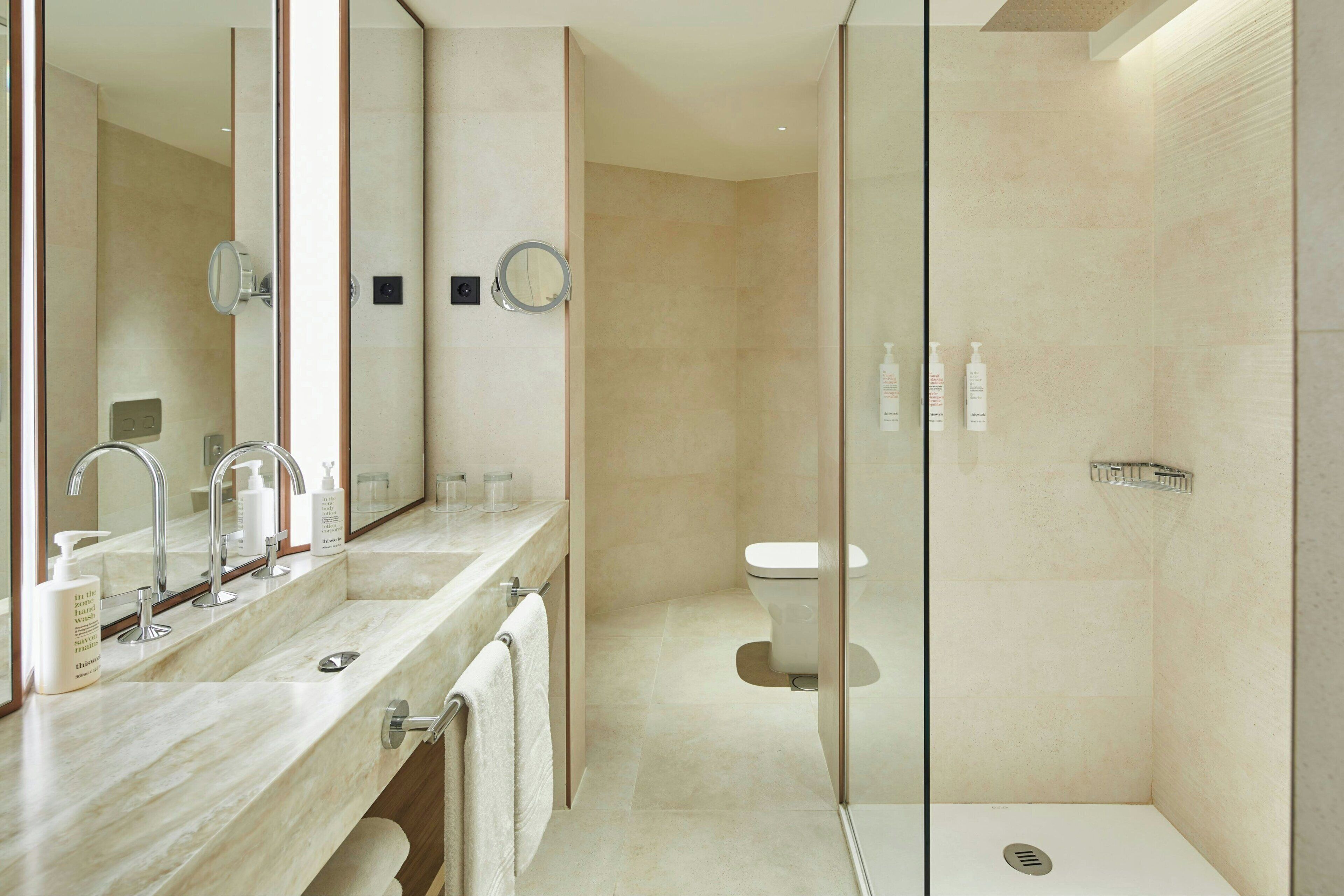 A modern bathroom with a marble vanity, a glass-enclosed shower, and a toilet.