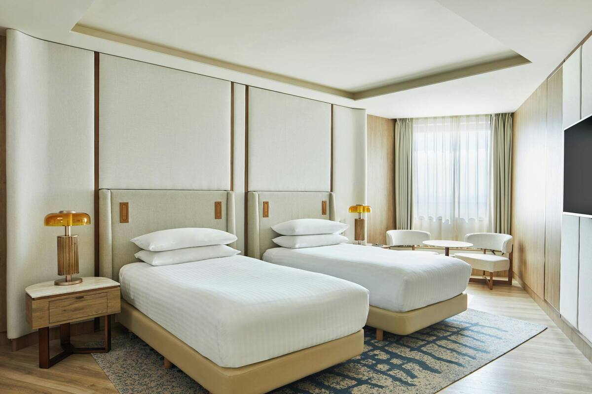 Une chambre d’hôtel avec deux lits, une télévision, un bureau et une chaise.