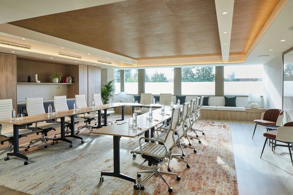 A conference room with a long table, chairs, and a high ceiling.