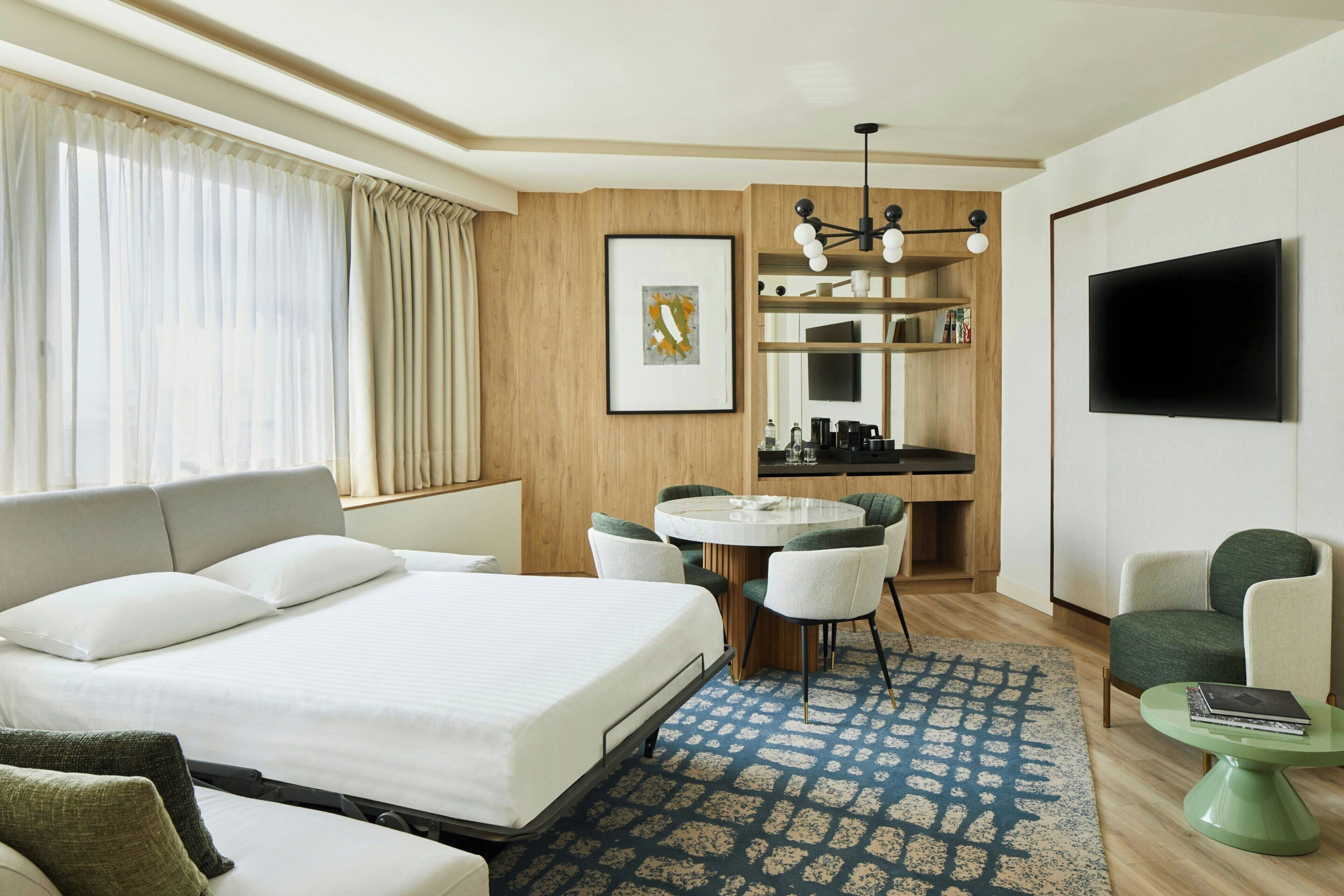 A hotel room with a bed, a desk, a chair, a television, and a coffee table.