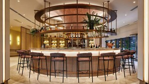 Un área de bar moderna con un mostrador circular, varios taburetes y un elemento decorativo central.