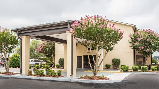 A hotel with a covered entrance, a beige facade, and pink flowering trees. - Quality Inn Mullins - Marion (Marion)