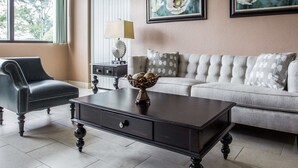 A living room with a sofa, a coffee table, a chair, and two framed floral paintings on the wall. - Quality Inn Mullins - Marion (Marion)