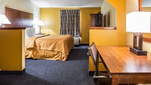 A hotel room with a bed, a desk, a chair, a television, and a mirror. - Quality Inn Mullins - Marion (Marion)