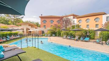 Alberca al aire libre, sombrillas en la alberca y camastros