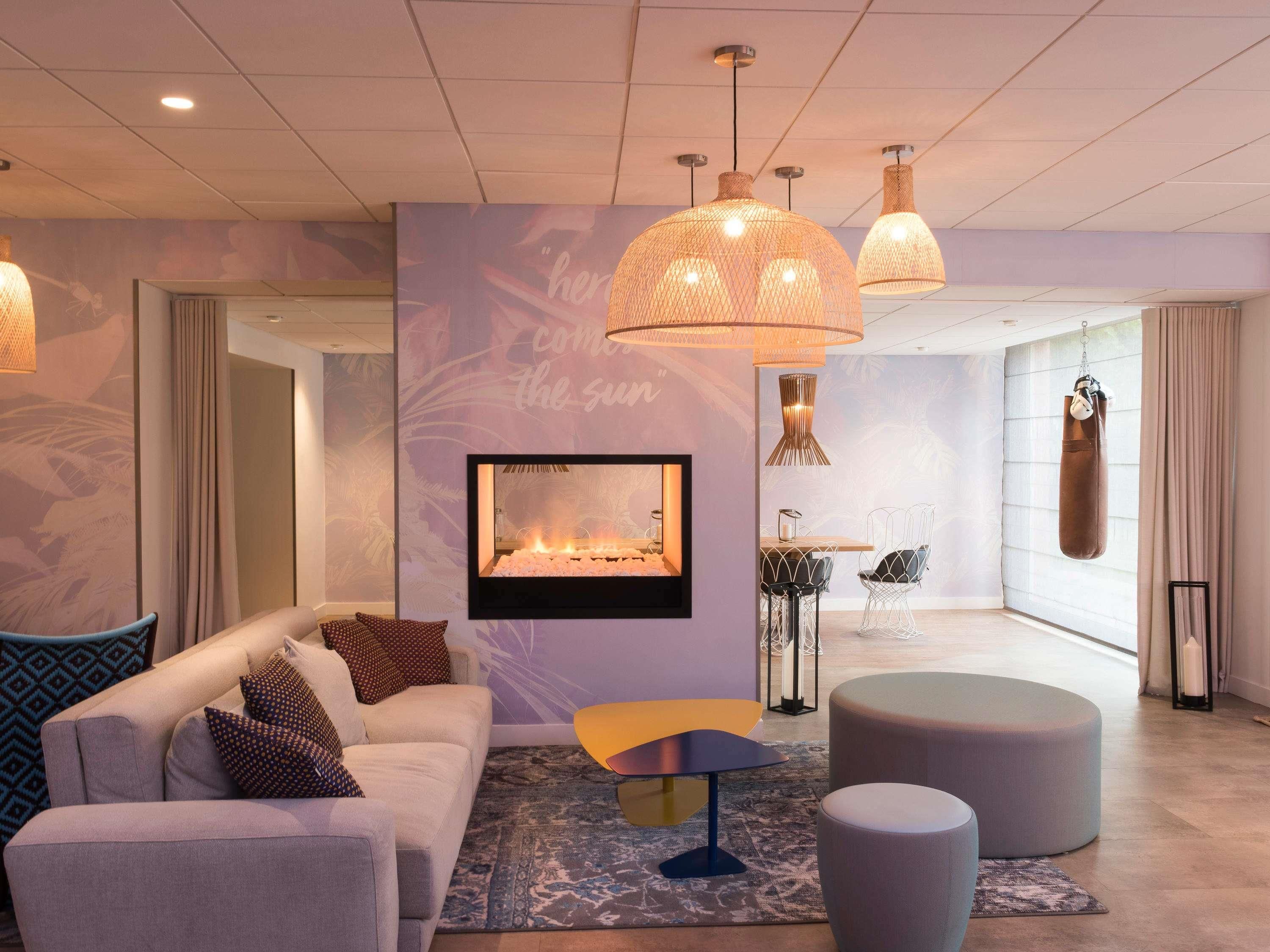 A modern living room with a sofa, ottoman, and a fireplace. There are hanging lights and a punching bag visible.