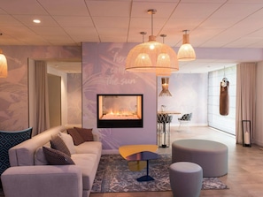 Una sala de estar moderna con sofá, reposapiés y chimenea. Se ven luces colgantes y un saco de boxeo.