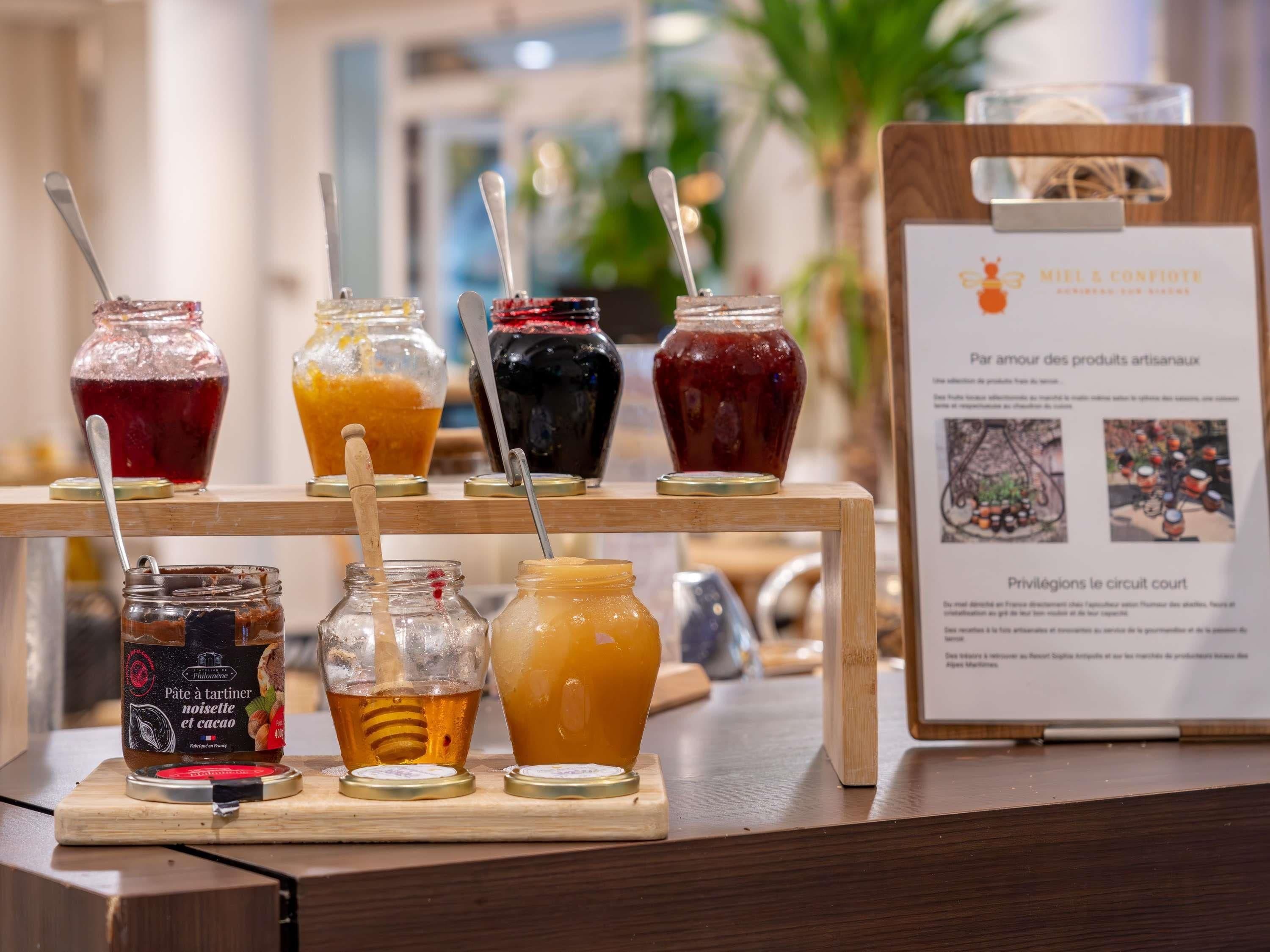 A display of various jams and honey jars on a wooden stand with a signboard in the background.