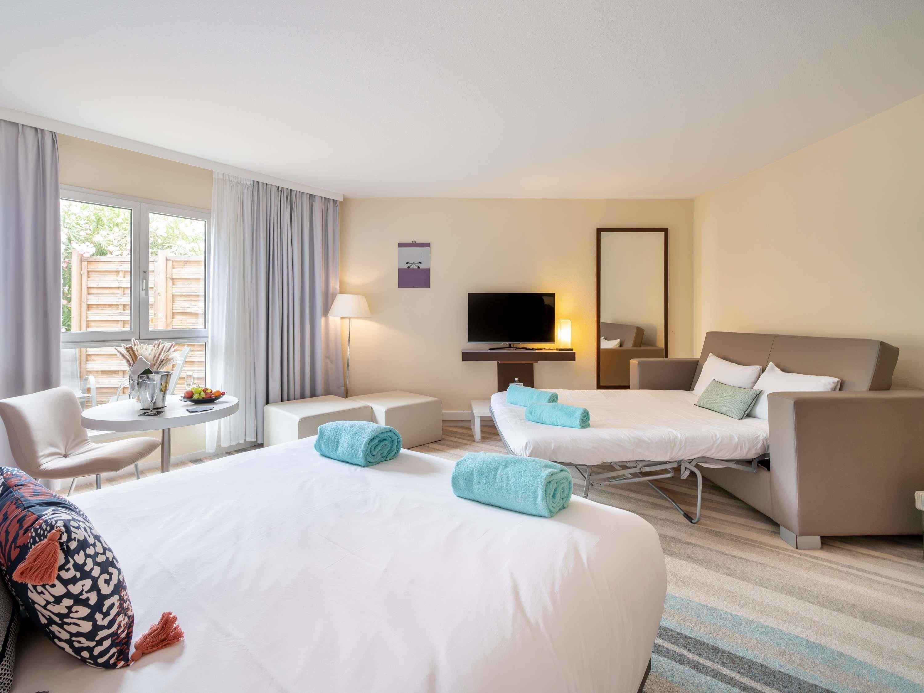 Une chambre d’hôtel avec deux lits, une télévision, un bureau et une chaise.